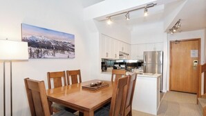 Eine kompakte Küche mit weißen Schränken, einer eingebauten Kochinsel mit Spüle und einem Kühlschrank.