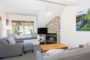 A living room with a fireplace, seating area, and a television. - Whistler Creekside Stay | Modern Kitchen & Scenic Views | Near Gondola (Whistler)