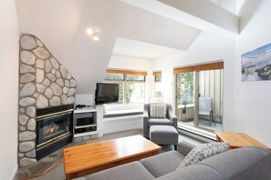 Ein modernes Wohnzimmer mit Kamin aus Stein, einem Flachbildfernseher und einer gemütlichen Sitzecke.