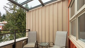Ein Balkon mit zwei Stühlen und einem kleinen Tisch, mit Blick auf ein Wohngebiet mit Bäumen und Häusern.