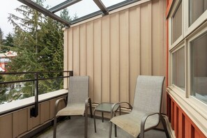 Ein Balkon mit zwei Stühlen und einem kleinen Tisch, mit Blick auf ein Wohngebiet mit Bäumen und Häusern.