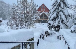 Ett snötäckt landskap med en byggnad som har ett rött tak och en träfasad.