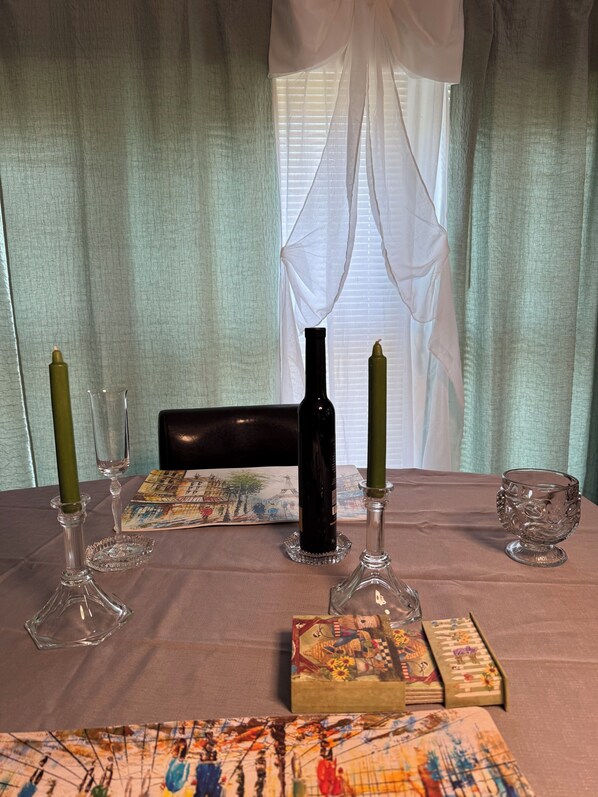 Taula de menjador amb espelmes, una ampolla de vi i una caixa decorativa.