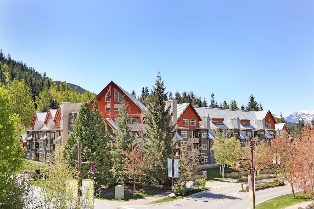 Ein Hotel mit mehreren Gebäuden mit roten Dächern, umgeben von Bäumen und einem Berg im Hintergrund.
