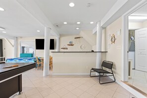 A spacious living area with a kitchen, dining space, and a visible laundry area. - Seas the Day North | Oceanfront Views, Huge Decks & Sleeps 17 (Virginia Beach)