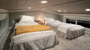 Un dormitorio con dos camas, una ventana y un techo con vigas de madera.