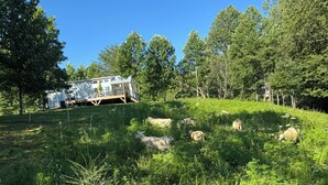 Un campo cubierto de hierba con una casa móvil blanca y una zona vallada.