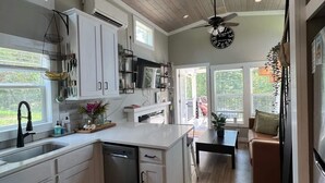 Una cocina moderna con armarios blancos, lavavajillas y un comedor con mesa y sillas.