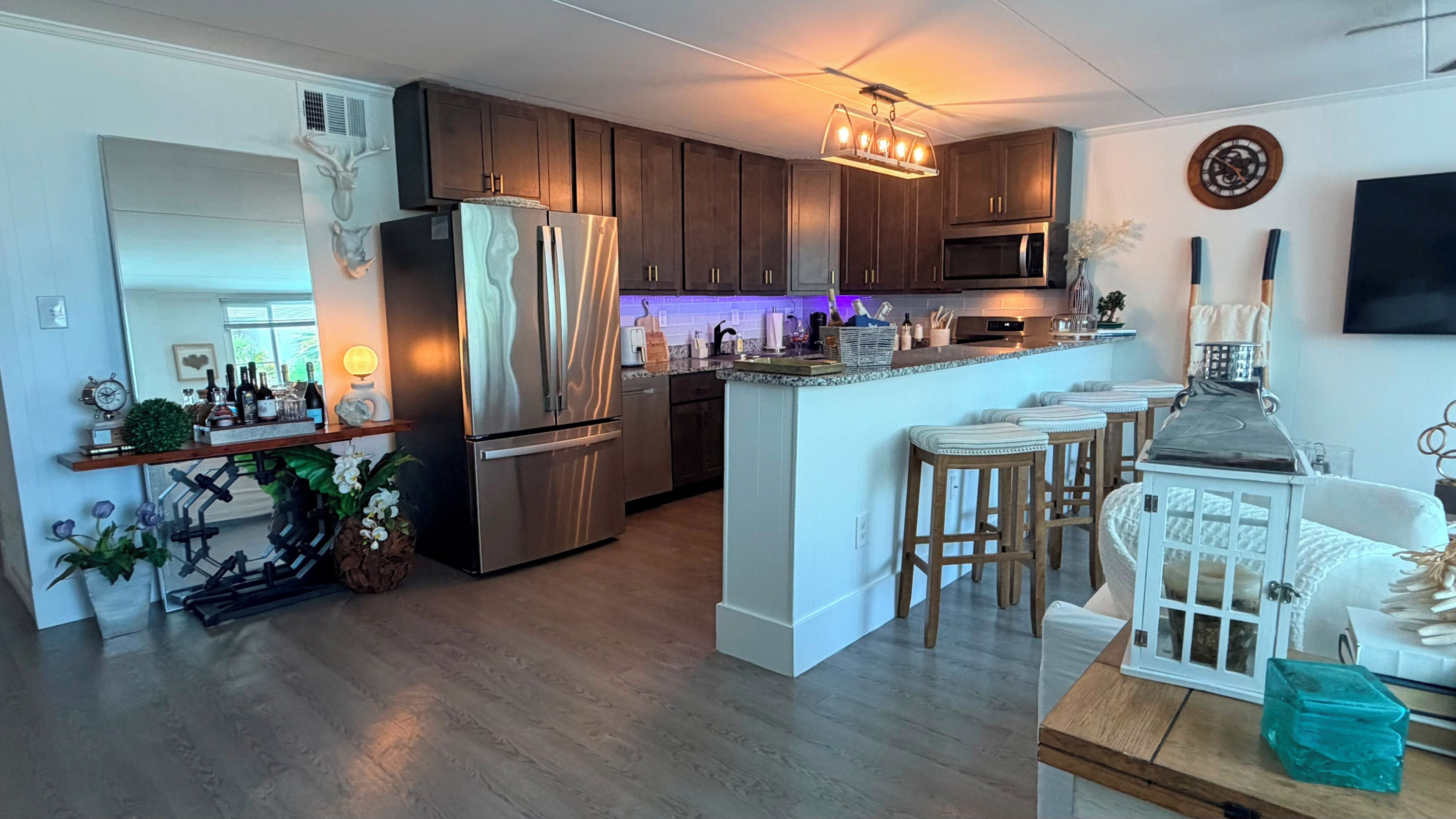 A modern kitchen with dark wood cabinets, stainless steel appliances, and a bar area with stools.