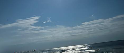 A beach with a clear sky, ocean waves, and a distant shoreline.