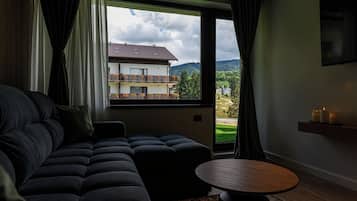 Ein modernes Wohnzimmer mit einem Ecksofa, einem runden Couchtisch und Blick auf ein Gebäude mit Balkonen.