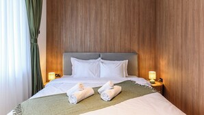 A hotel room with a bed, two bedside lamps, a green throw blanket, and two rolled towels. - Grand Chalet Suite 2 (Poiana Brașov)