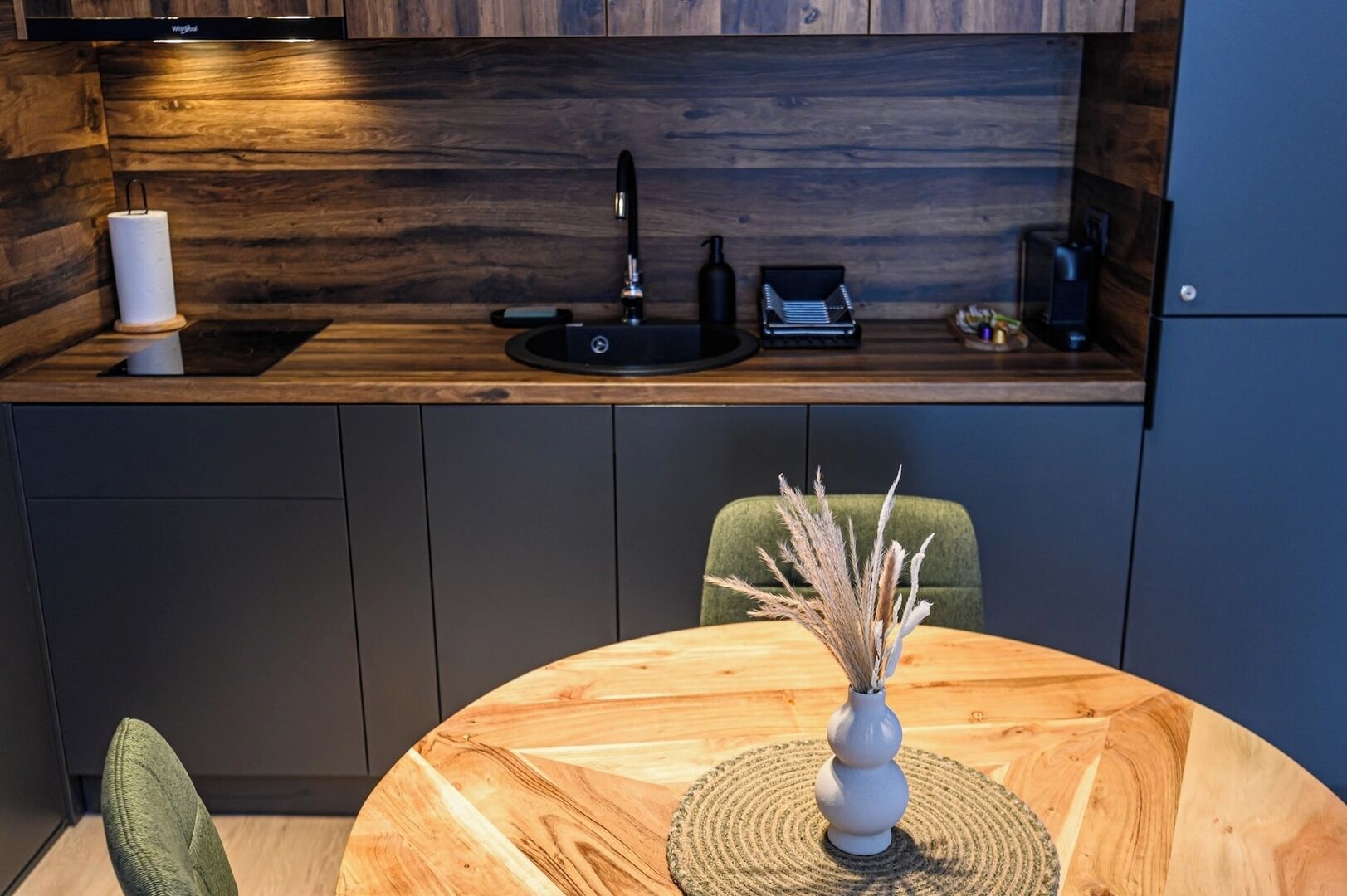 A modern kitchen with a wooden countertop, a sink, and a coffee machine.