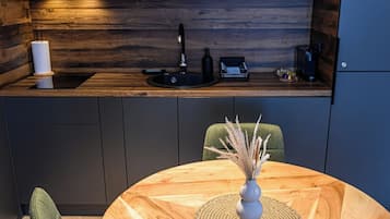 A modern kitchen with a wooden countertop, a sink, and a coffee machine.