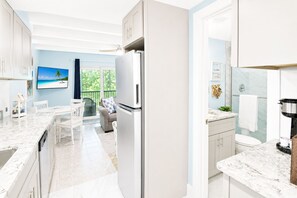 A modern kitchen with a built-in refrigerator, a dining area with a view, and a bathroom with a shower. - Sanibel Island - Walk to Beach Colony Inn 10 (Sanibel)