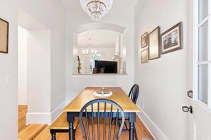 A dining area with a wooden table, chairs, and a chandelier. - The Oglethorpe Retreat of 1872 | Walk Everywhere (Savannah)
