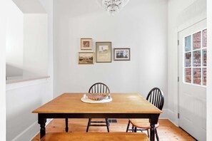 A dining room with a wooden table, four chairs, and a chandelier. - The Oglethorpe Retreat of 1872 | Walk Everywhere (Savannah)