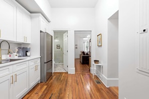 A kitchen with white cabinets, a stainless steel refrigerator, and a coffee maker. - The Oglethorpe Retreat of 1872 | Walk Everywhere (Savannah)