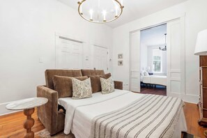 Ein Schlafzimmer mit einem Bett, einem runden Tisch, einer Lampe und einer Tür zu einem anderen Raum.