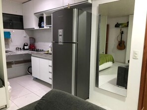 A compact kitchen with a refrigerator, microwave, and a coffee maker. - Apartment in Boa Viagem. 700 meters from the beach, 10 minutes from the airport. (Recife)