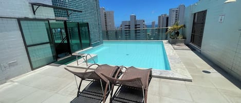 A rooftop pool with a clear view of the city skyline, surrounded by high-rise buildings.