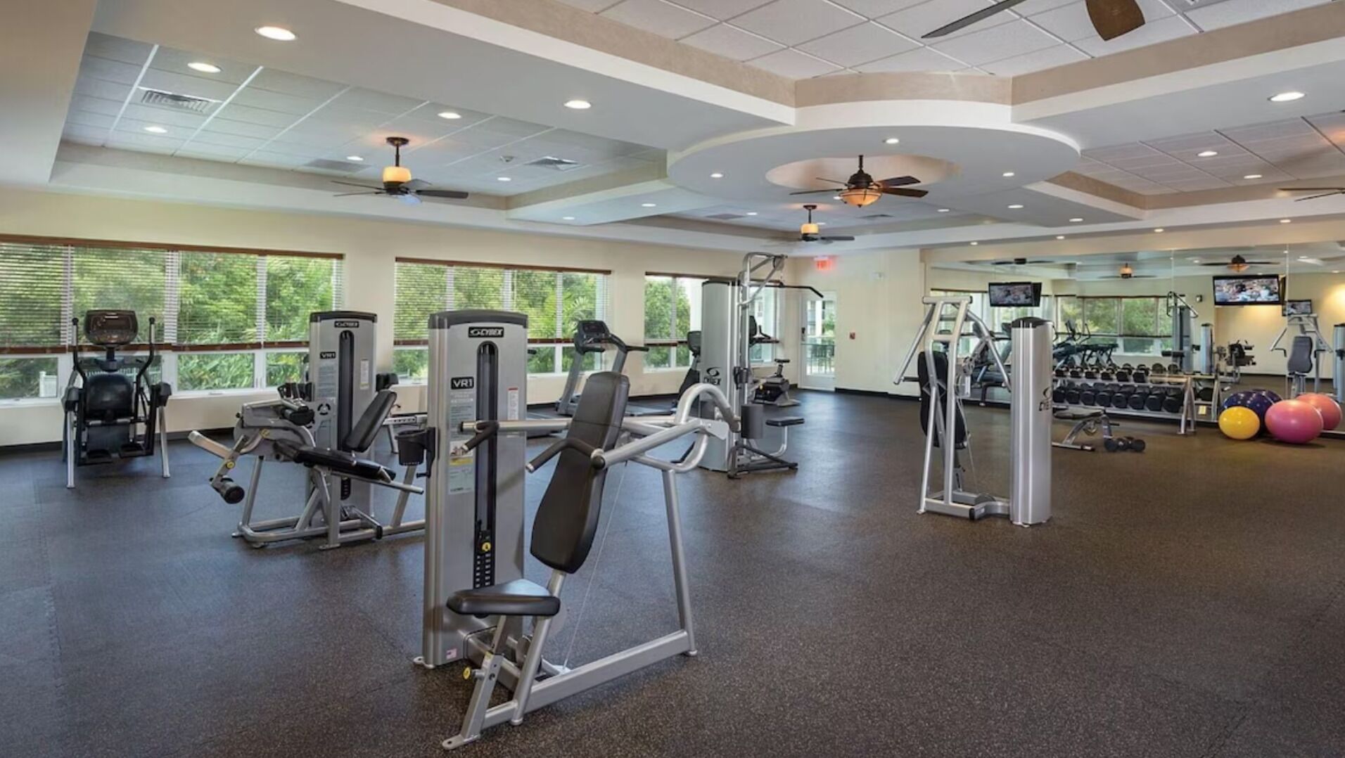 A gym with various exercise machines, a television, and a large window.