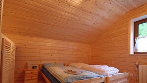 A wooden cabin bedroom with a single bed, a nightstand, a window, and a radiator. - Baum-Hüsli, (Grächen). 8-Bettwohnung by Interhome (Grächen)
