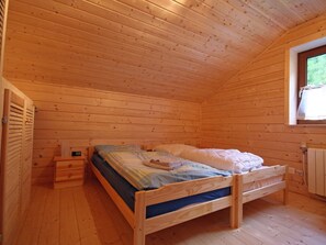 A wooden cabin bedroom with a single bed, a nightstand, a window, and a radiator. - Baum-Hüsli, (Grächen). 8-Bettwohnung by Interhome (Grächen)