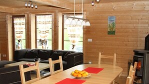 A cozy living room with a sofa, a dining table with chairs, and a fireplace. - Baum-Hüsli, (Grächen). 8-Bettwohnung by Interhome (Grächen)