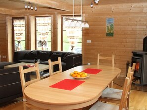 A cozy living room with a sofa, a dining table with chairs, and a fireplace. - Baum-Hüsli, (Grächen). 8-Bettwohnung by Interhome (Grächen)