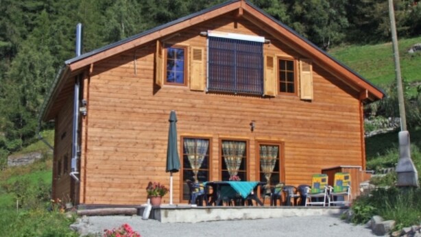 A wooden cabin with a porch, a table, and chairs. - Baum-Hüsli, (Grächen). 8-Bettwohnung by Interhome (Grächen)