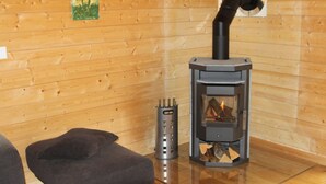 A room with a wood-burning stove, a grey upholstered bench, and a metal ashtray. - Baum-Hüsli, (Grächen). 8-Bettwohnung by Interhome (Grächen)