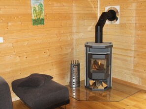 A room with a wood-burning stove, a grey upholstered bench, and a metal ashtray. - Baum-Hüsli, (Grächen). 8-Bettwohnung by Interhome (Grächen)
