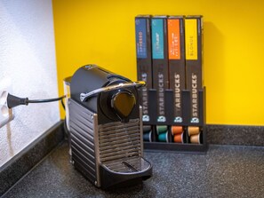 A coffee machine with a power cord plugged in, a coffee pod holder with multiple pods, and a yellow wall in the background. - Ambassador "Yellow Home", (Grächen), 1048 by Interhome (Grächen)