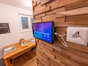 A tablet mounted on a wooden wall with a power outlet and a window in the background. - Ambassador "Yellow Home", (Grächen), 1048 by Interhome (Grächen)