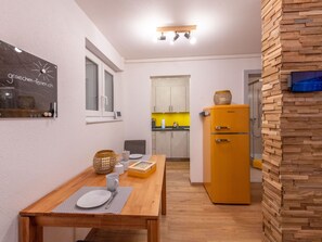 A compact kitchen with a wooden table, a yellow refrigerator, and a wall-mounted light fixture. - Ambassador "Yellow Home", (Grächen), 1048 by Interhome (Grächen)