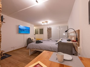 A modern bedroom with a bed, a desk, a chair, a TV, and a radiator. - Ambassador "Yellow Home", (Grächen), 1048 by Interhome (Grächen)
