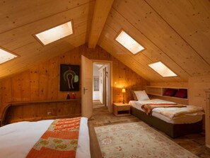 A cozy attic bedroom with wooden walls, a bed, a nightstand, and a lamp. - Chalet François, (Champery). by Interhome (Champery)