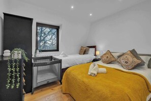 Ein Schlafzimmer mit einem Bett, einem Nachttisch, einem Fenster und einem kleinen Schreibtisch mit Pflanze.