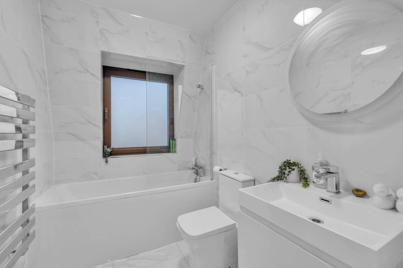 A modern bathroom with a bathtub, toilet, and sink.