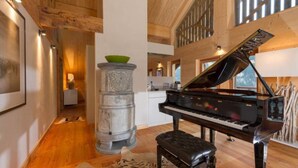 A grand piano in a spacious room with wooden floors and a large window. - Chalet François, (Champery). by Interhome (Champery)