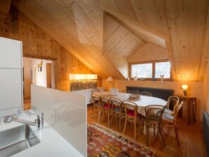 Ein gemütliches Dachzimmer mit Esstisch, Stühlen, Heizkörper und Fenster.