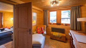 L’intérieur d’un chalet en bois accueillant, avec un lit, une petite table, un radiateur et une fenêtre avec des rideaux.