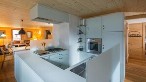 Une cuisine moderne avec des meubles blancs, un îlot central et un four encastré.