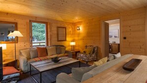 L’intérieur d’un chalet en bois chaleureux et accueillant, avec un canapé, un fauteuil et une table à manger.