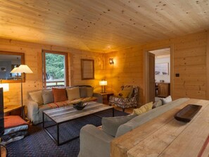 Ein gemütliches Holzhaus-Interieur mit einer Couch, einem Sessel und einem Esstisch.