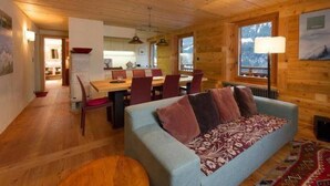 Ein gemütliches Blockhaus-Interieur mit Essbereich, einer Couch und einem großen Fenster.