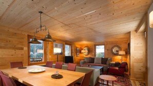 Ein Holzinterieur mit Esstisch, Stühlen, einer Couch und einem kleinen runden Tisch.