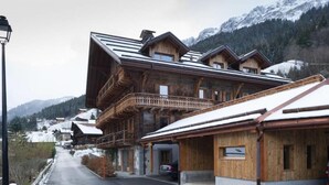 Eine Holzhütte mit Balkon, überdachter Eingang und Blick auf schneebedeckte Berge.