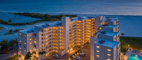 A hotel with multiple floors, a swimming pool, and a view of the ocean.